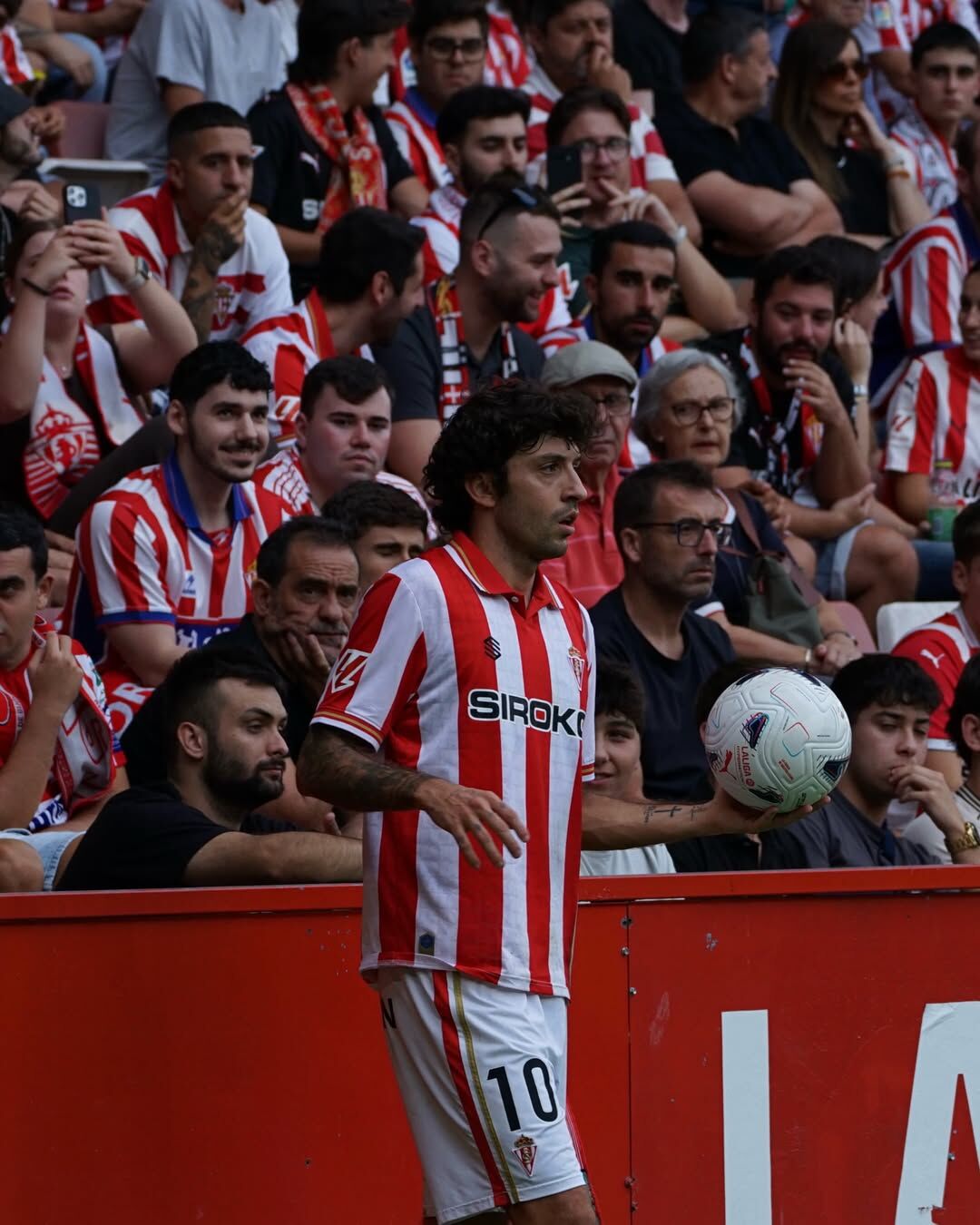 César Gelabert junto a la valla publicitaria con la afición al fondo